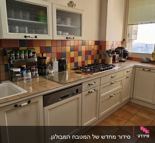 מטבח מאורגן עם ארונות, כיריים וכלים על השיש